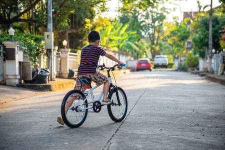 Young asian boy ride bicycles in the village alone in the evening.の写真素材