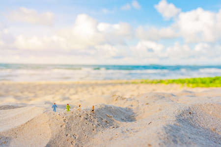 minifigure doll idea image of four runner running on sand beach with blur beautiful sea on day time in background.の写真素材