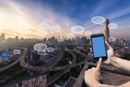 Hand holding smartphone and cityscape with communication and speech icon,Technology and...