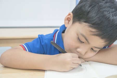 Little kid is writing on the tableの写真素材