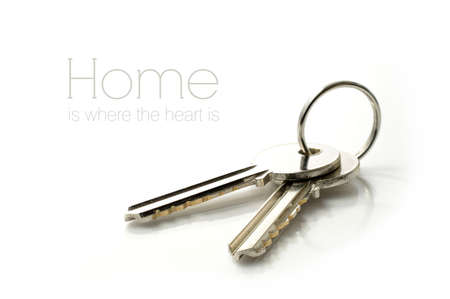 Studio macro of stainless steel house keys on glass against a white background. Copy space.の写真素材