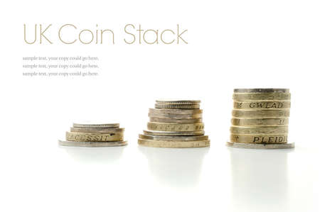 Studio macro image of UK currency coins stacked with soft shadows against a white background. Copy space.の写真素材