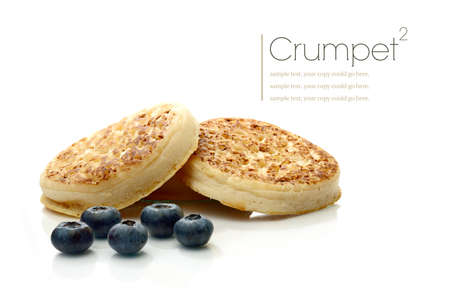 Studio macro of stacked English Crumpets (Pikelet) and scattered blueberries with soft shadows on a...