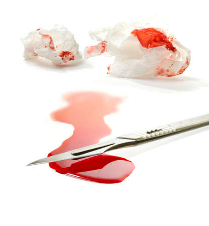 Concept stock image for clinical negligence or clinical malpractice. Surgical steel scalpel, pool of blood and blood stained tissues against white background. Copy space.の写真素材