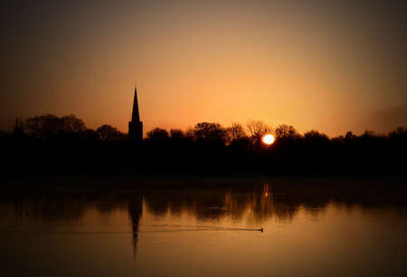 Spring morning sunrise over English nature reserve with neighbouring village church. Copy space.の写真素材