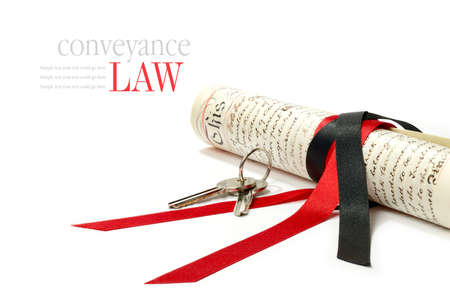 Concept image depicting conveyance law with legal scroll and house keys against a white background....