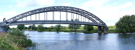 Panoramic image of a metal bridge spanning the River Trent before the mouth of the River Derwent, Nottinghamshire, England の写真素材