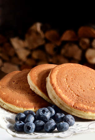 Homely and rustic, fresh soft stacked Scotch pancakes with ripe blueberries on a cotton napkin....