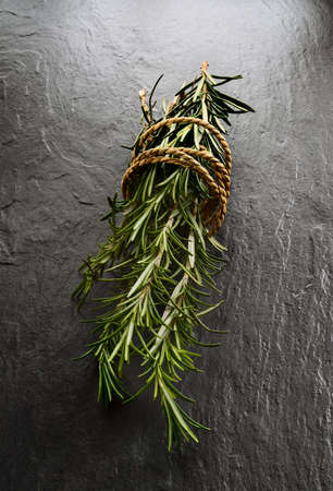 Fresh Rosemary - Rosmarinus officinalis - tied with string on grey slate  Shot in mystic light style...