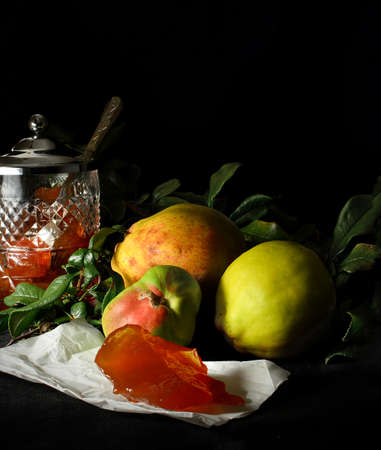 Selectively lit Quince fruit and Quince jelly against a dark background. Copy space.の写真素材