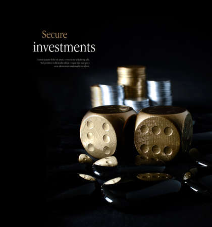 Concept image for secure financial planning. Creatively lit, stacked generic gold and silver coins representing client investment or savings with dice representing risk. Copy space.の写真素材