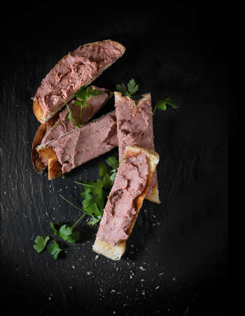 Creatively lit aerial shot of chicken liver pate on toast with parsley garnish. Copy space.の写真素材