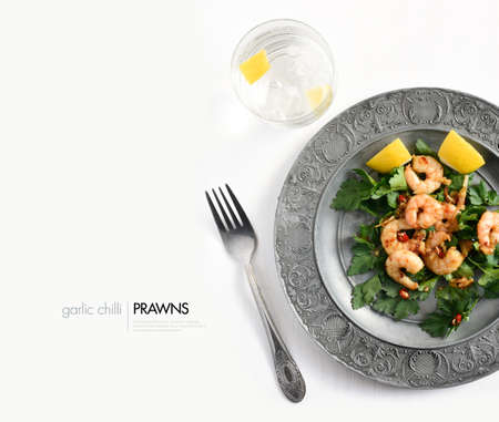 Aerial view of grilled chilli and garlic prawns on a bed of parlsey with chillies and lemon garnish against a white background. Copy space.の写真素材