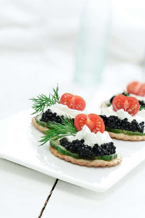 Delicious cream cheese, cucumber and caviar canapes against white. Copy space.の写真素材