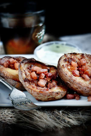 Grilled potato skins with bacon and cheddar cheese in a rustic setting with appropriate side dish and soda drink. Selective focus and copy space.の写真素材
