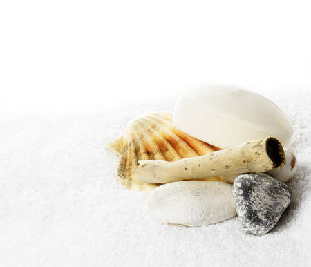 Concept image for spa therapy. Sea shells and pumice stones on a white fluffy towel against a white background. Copy space.の写真素材