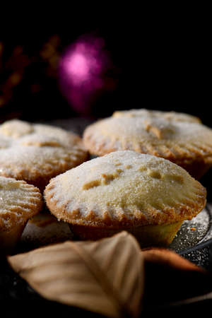 Festive luxury all butter mince pies, a traditional British Christmas dessert, creatively lit against a seasonal background. Generous accommodation for copy space.の写真素材