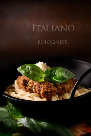 Classic Italian Spaghetti Bolognese with Parmesan cheese and basil herb garnish, set against a rustic background with copy space. The perfect image for your Italian menu cover design art.の写真素材