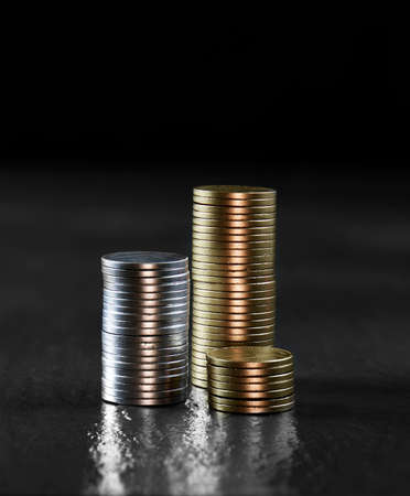 Generic gold and silver stacked coins against a dark background. Concept image for investment,...