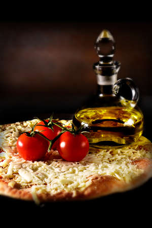 Classic Italian margherita pizza smothered with grated mozzarella cheese and tomato sauce shot against a rustic background with creative lighting. the perfect image for your take-away menu or bistro menu cover art.の写真素材