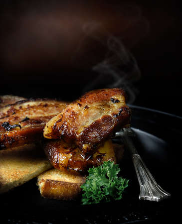 Creatively lit roasted belly pork against a rustic background with generous accommodation for copy space. The perfect image for your bistro or restaurant menu cover art design.の写真素材