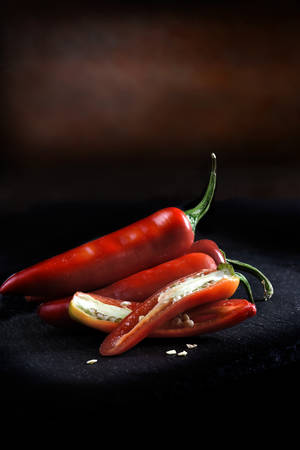 Creatively lit red chilli peppers against a dark rustic background with generous accommodation for copy space.の写真素材