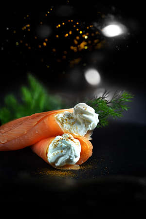 Festive image for seasonal holidays - smoked salmon filled with cream cheese with Paprika sprinkles shot against a dark background with generous accommodation for copy space.の写真素材