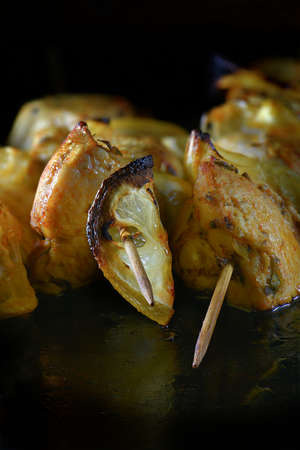 Skewered chicken pieces on bamboo skewers with lemon wedges, grilled and ready for eating. Shot against a dark background with generous accommodation for copy space.の写真素材