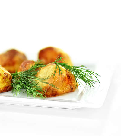 Roast potatoes with dill garnish shot against a white background with generous accommodation for copy space.の写真素材