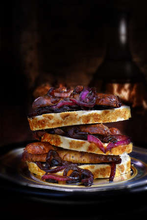 Ultimate stacked pork sausage and caramelized red onion garnish stacked sandwich against a rustic background. Generous accommodation for copy space.の写真素材