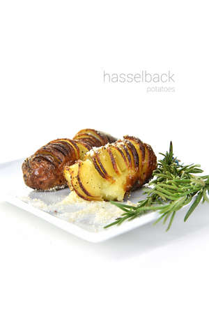 Roasted Hasselback Potatoes with parmesan cheese and rosemary herb garnish shot against a white background with generous accommodation for copy space.の写真素材