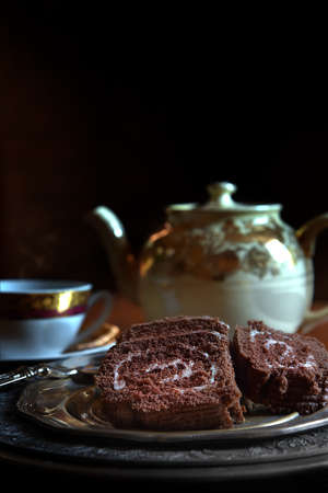 A dark, rustic and creatively lit concept image for the very traditional English afternoon tea with slices of festive chocolate sponge yule log. Generous accommodation for copy space, perfect image for your menu cover art.の写真素材