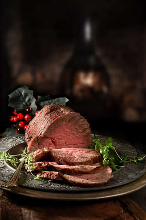 Succulent prime roast beef topside rump joint carved and ready for serving. Shot against a rustic, festive background with generous accommodation for copy space.の写真素材