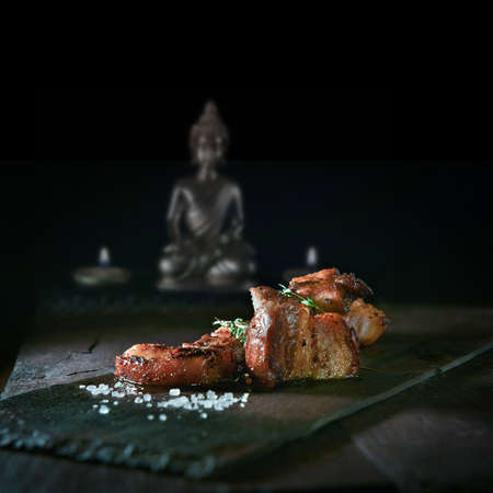 Szechuan pork grilled with traditional Chinese spices, prepared for serving with a thyme herb garnish. The perfect image for your fine dining cover art menu designs. Copy space.の写真素材