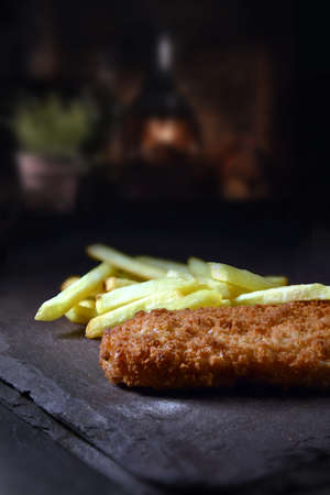 Breaded cod fillet and chips shot against a rustic background with generous accommodation for copy space.の写真素材