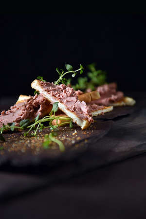 Traditional chicken liver pate with fresh thyme herbs shot on old slate  against a black background...