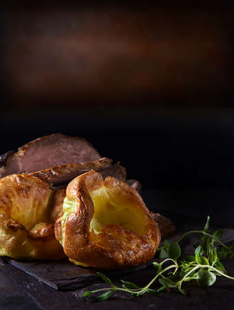 Traditional British Yorkshire puddings served with prime roast beef and thyme herb garnish. Shot...