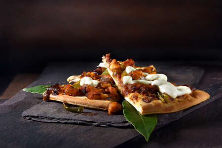 American Texan BBQ chicken pizza served with fresh bay leaves and shot against a dark rustic background with generous accommodation for copy space.の写真素材