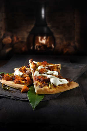 American Texan BBQ chicken pizza served with fresh bay leaves and shot against a dark rustic background with generous accommodation for copy space.の写真素材