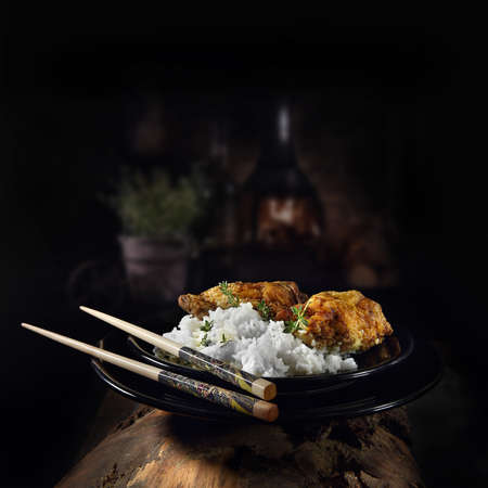 Marinated chicken thighs in coconut milk and then roasted with Moroccan spices served with steamed Basmati rice shot against a dark rustic background. The perfect image for your menu cover art.の写真素材