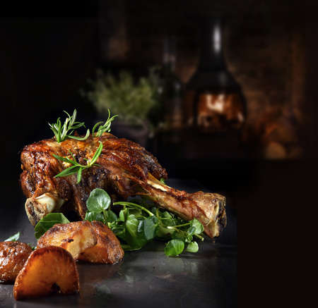 Roasted shoulder of lamb with rosemary, garlic, watercress garnish and roasted potatoes. Shot against a rustic background with generous accommodation for copy space.の写真素材