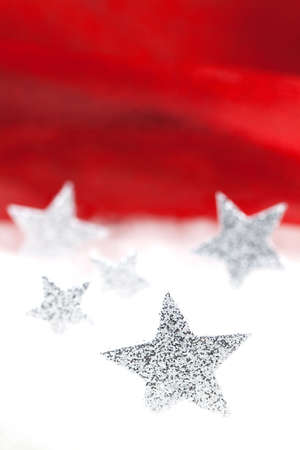 silver stars in snow in front of red backgroundの写真素材
