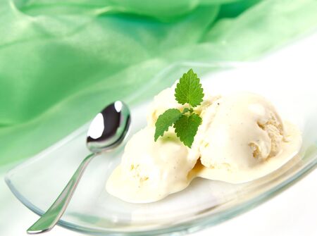 vanilla ice cream with mint and spoon on plateの写真素材