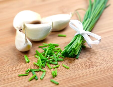 sliced chives and garlic on wooden boardの写真素材