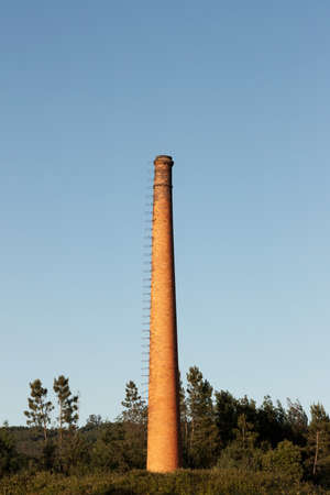 Industrial Old Brick Chimney without smoke, against on blue sky and woodsの写真素材