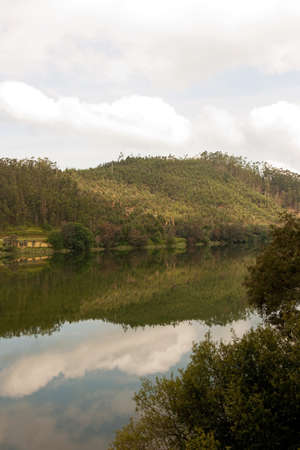 Landscape of a moutain and woods with its reflection in the riverの写真素材