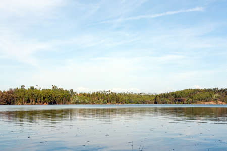 Landscape of a woods and sky with its reflection in the riverの写真素材
