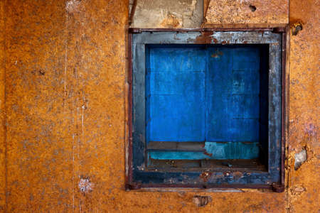 dirty old orange wall with small blue enclosure
