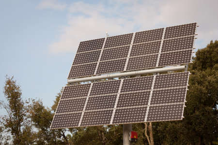 small solar panel against trees and skyの写真素材