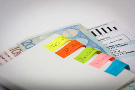 bills to pay with some post-it and banknotes inside an bookの写真素材